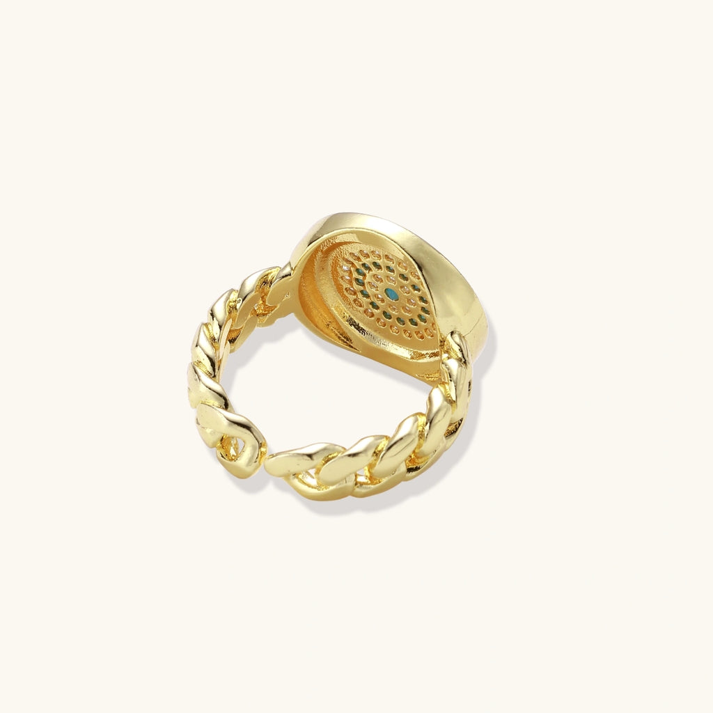 Gold chain ring with Greek key border and turquoise evil eye center on white background